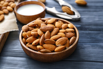 Bowl with tasty almonds on wooden background