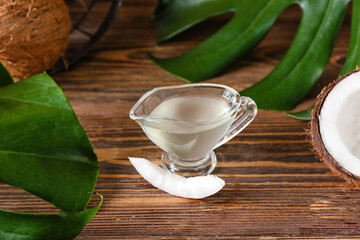 Gravy boat of coconut oil on wooden background