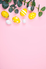 Happy easter concept. Yellow eggs and a branch of eucalyptus on a pink pastel background. Flat lay, top view, copy space. Vertically.