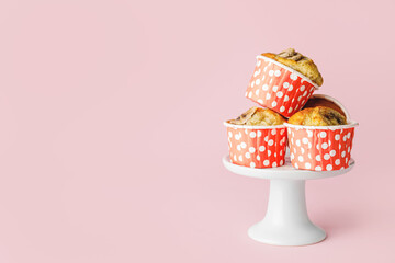Dessert stand with tasty banana muffins on color background