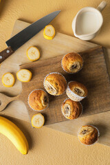 Board with tasty banana muffins on color background