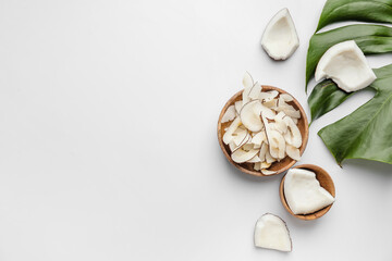 Bowl with tasty coconut chips on light background