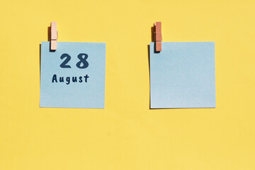 August 28. 28th day of the month, calendar date. Two blue sheets for writing on a yellow background. Top view, copy space. Summer month, day of the year concept