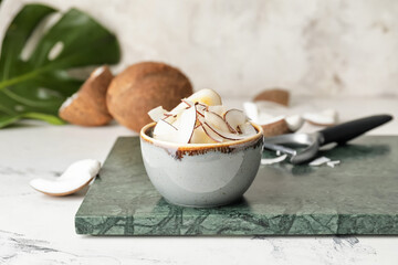 Bowl with tasty coconut chips on table