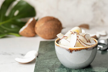 Bowl with tasty coconut chips on table