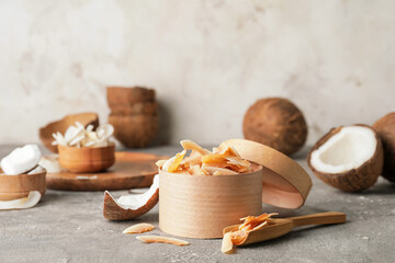 Box with tasty coconut chips on grey background