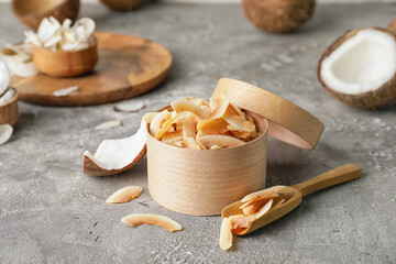 Box with tasty coconut chips on grey background