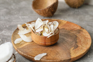 Fototapeta na wymiar Bowl with tasty coconut chips on grey background