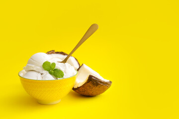 Bowl with tasty coconut ice cream on color background