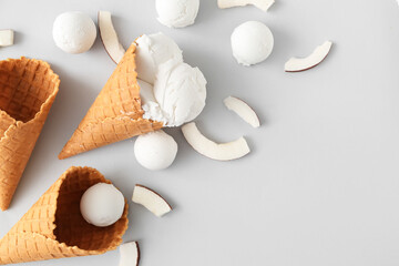 Waffle cones with tasty coconut ice cream on light background