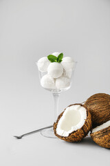 Glass with tasty coconut ice cream on light background