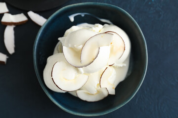 Bowl with tasty coconut ice cream on dark background
