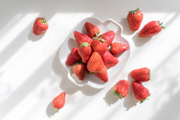 Fresh strawberries in plate on the white table. Heap of Red strewberry on plate close up. Top view.