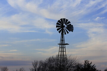 Windmill at Sunset with white clouds north of Hutchinson Kansas USA out in the country.