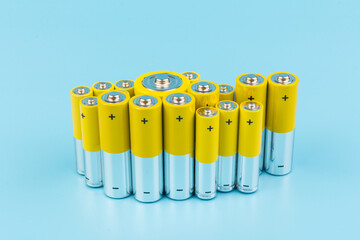 Photo of gray-yellow alkaline AA batteries on blue background. Recycling of rechargeable NiMH batteries. The most popular size of accumulators. Copy space.