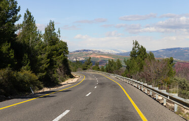 A road  in the Upper Galilee against the backdrop of snow-capped mountain peaks in Lebanon, in northern Israel