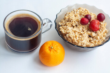 Breakfast on white background, oatmeal with berries, coffee and fruit and tangerine