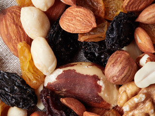 Close up at Mix nuts in wooden plate on wooden table background.Nuts including Cashew,walnuts,almonds, brazilian nuts,pecan and macadamia.Intake a handful of nut a day can stave off various disease.