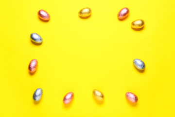 Frame made of sweet chocolate eggs on color background