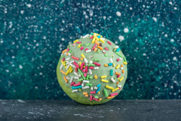 Green cookie with sprinkles on blue background
