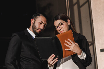 A couple of entrepreneurs analyze their work schedule at the company entrance.
