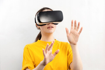 A portrait of a young pretty woman wearing virtual reality glasses, holding out her hands, trying to touch something. White background. The concept of virtual reality