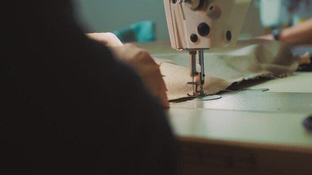 Close up of fashion designer hands stitching cloth using sewing machine