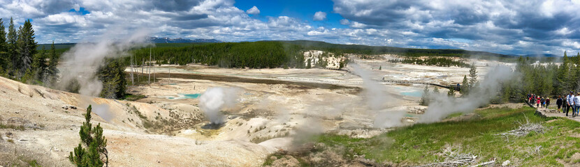YELLOWSTONE, MONTANA - JULY 10, 2019: Tourists visit the famous geysers and pools on a beautiful summer day - Panoramic view