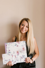 The girl holds in her hands beautiful photo albums or photo books in the spring style