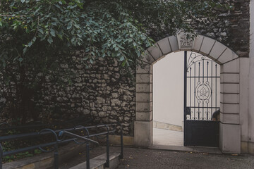 Obraz premium The entrance to a Monastery foundation Paulinow na Skalka in the Christian part of Kazimierz district in Krakow, closed by a rusty metal grating in arch. Iron arched gate in an old stone wall with ivy