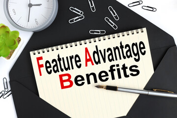 Business Acronym FAB - Feature Advantage Benefits. text on a sheet of notepad on a black envelope...