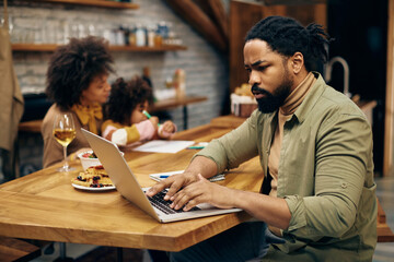 African American father working on laptop at home.
