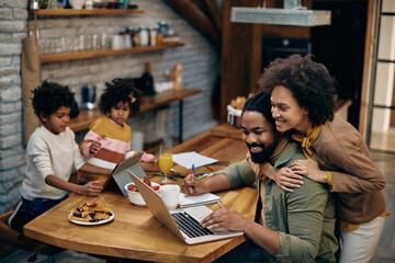 Happy African American family using wireless technology at home.
