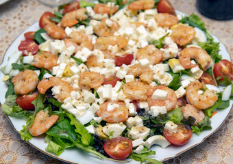 Vegetable salad with shrimps, cheese, iceberg lettuce and cherry tomatoes on a light background. Healthy food. Selective focus.