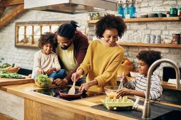 Happy African American family preparing a meal in the kitchen.