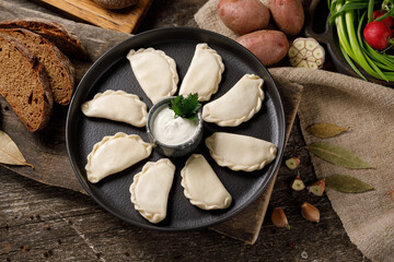 Appetizing traditional Russian dumplings, hand-made with potatoes. Still life on a wooden board....