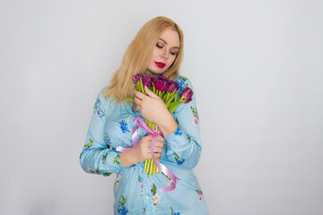 Blonde woman in floral dress holding purple tulips in her hands