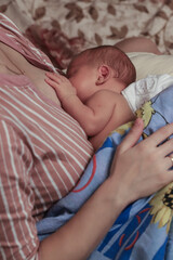baby sucks mother's breast and holds a plump hand on her breast, breastfeeding