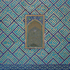 Beautiful blue and turquoise mosaic decor around latticework window on exterior wall of Sher Dor madrassa, a monument of famous historic medieval Registan Square in Samarkand, Uzbekistan