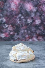 White meringue cookies with black raisines on a concrete background