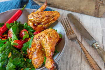 Keto meal with grilled chicken and fresh green salad with strawberries  served with pumpkin seed oil and chilis