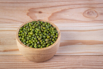 Green beans in a wooden cup placed on a wood panel, Selective focus.