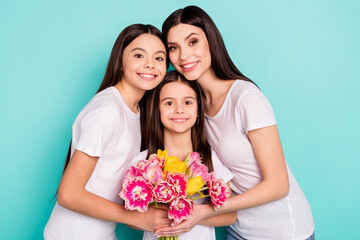 Photo portrait of three young sisters in white t-shirts keeping tulips bouquet in spring isolated bright blue color background