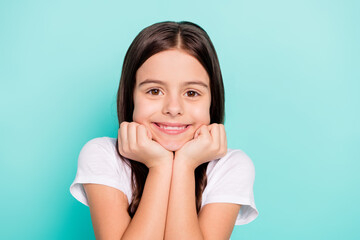 Photo of shiny sweet little girl wear white t-shirt smiling arms chin cheek isolated turquoise color background