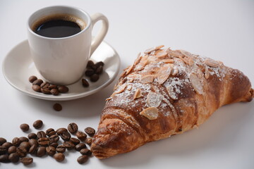 Fresh croissant with a cup of coffee, roasted beans on vintage background