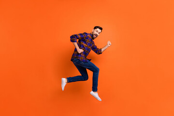 Fototapeta na wymiar Full length portrait of cheerful excited handsome guy running open mouth isolated on orange color background
