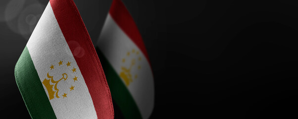 Small national flags of the Tajikistan on a dark background