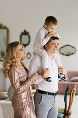 Fototapeta premium Beautiful young family man woman and son in smart clothes in a luxurious bright interior, happy family