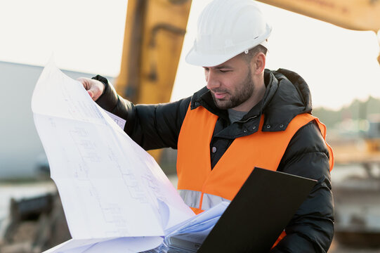 Engineering Consulting on construction site holding blueprint in his hand. Building inspector. Construction site check drawing and business workflow of the project.