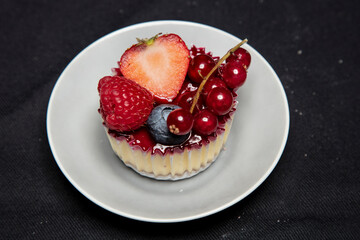 beautiful and tasty looking cheesecake on a black background, covert with fruit, view from above